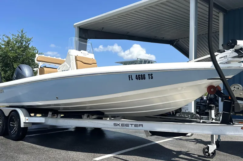Slide: The Image of 2023 Skeeter SX210 boat on trailer, parked under a metal canopy. - 1