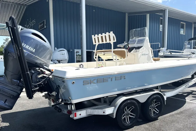 Slide: The Image of 2023 Skeeter SX210 boat with Yamaha engine on trailer, parked outside a blue building. - 10