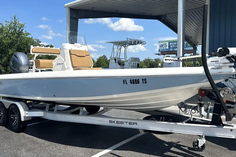 Slide: The Image of 2023 Skeeter SX210 boat on trailer, parked outdoors under a canopy. - 9