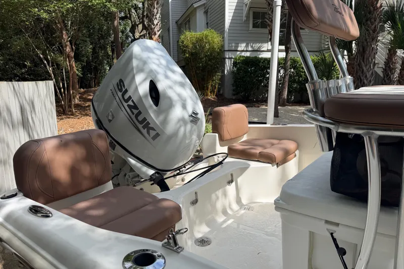 Slide: The Image of 2023 Pioneer 180 Islander boat interior with Suzuki outboard motor and cushioned seating. - 10