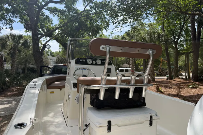 Slide: The Image of 2023 Pioneer 180 Islander boat interior with console and seating, surrounded by trees. - 14