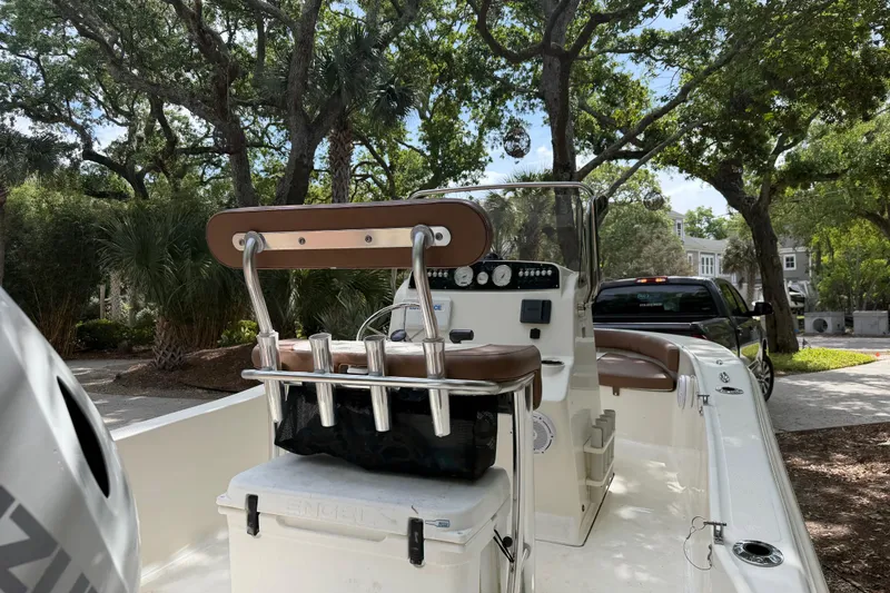 Slide: The Image of 2023 Pioneer 180 Islander boat with seating, parked outdoors under trees. - 15