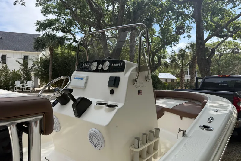 Slide: The Image of 2023 Pioneer 180 Islander boat interior with steering console and seating, surrounded by trees. - 16