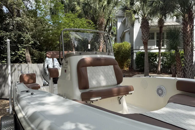 Slide: The Image of 2023 Pioneer 180 Islander boat with brown seating, parked near palm trees. - 17