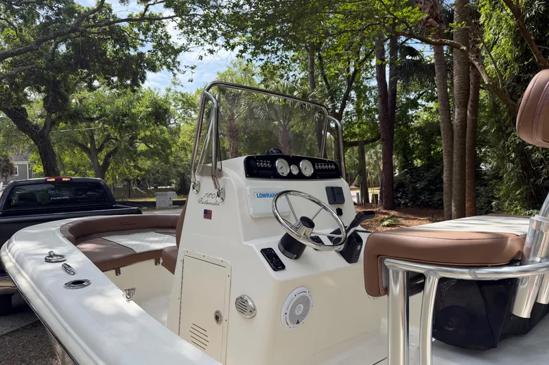 Slide: The Image of 2023 Pioneer 180 Islander boat with sleek console and comfortable seating in a wooded setting. - 18