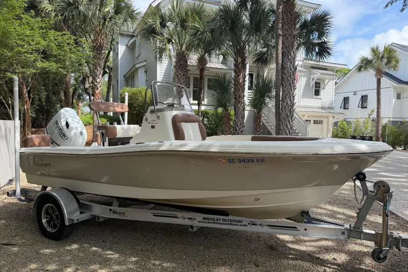 Slide: The Image of 2023 Pioneer 180 Islander boat on trailer, parked near palm trees and houses. - 3