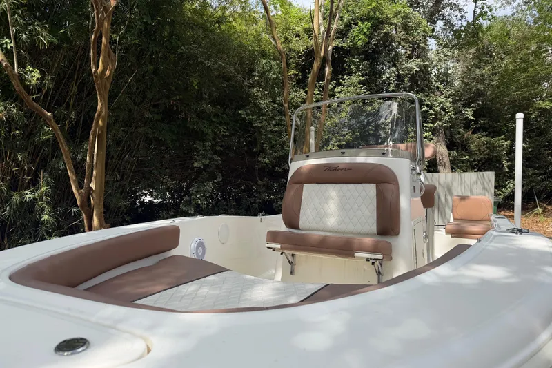 Slide: The Image of 2023 Pioneer 180 Islander boat with brown seating, surrounded by lush greenery. - 5