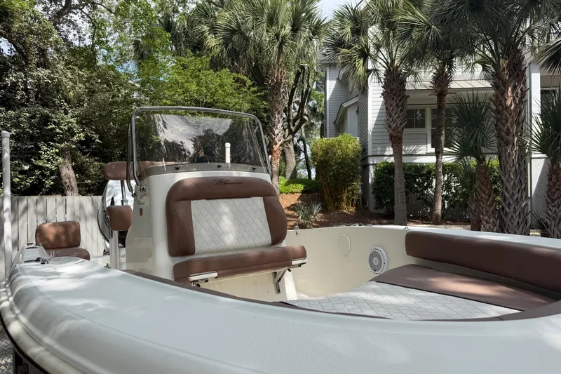 Slide: The Image of 2023 Pioneer 180 Islander boat with brown seating, surrounded by palm trees. - 6