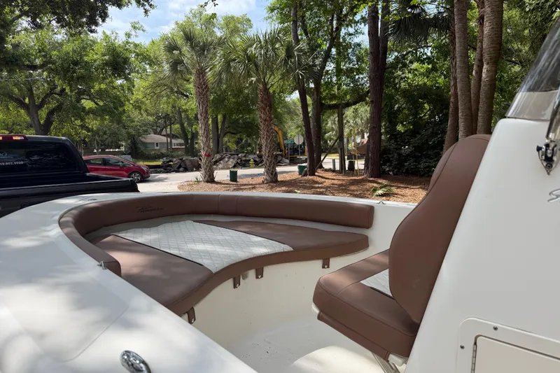 Slide: The Image of 2023 Pioneer 180 Islander boat interior with brown seating, parked near trees. - 7