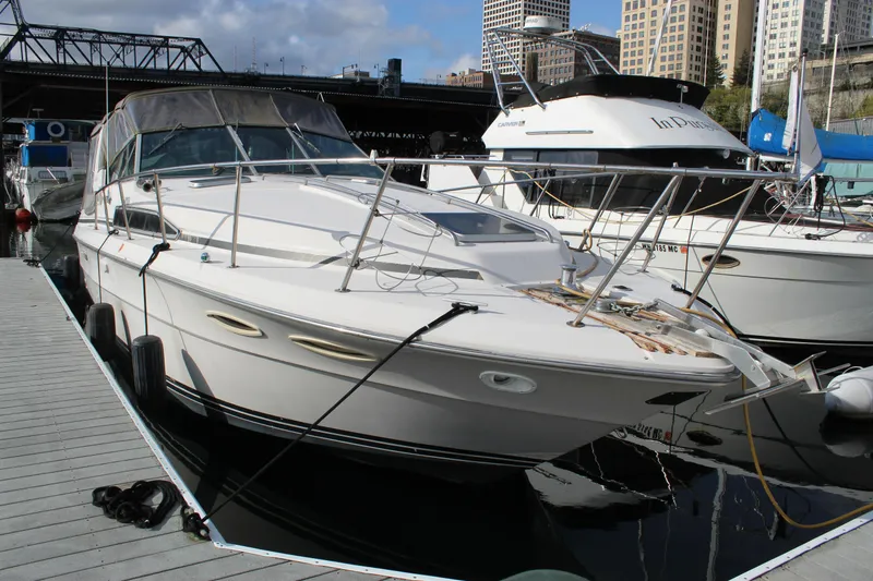 The Image of 1986 Searay 340 Express docked at marina with city skyline background. - 0