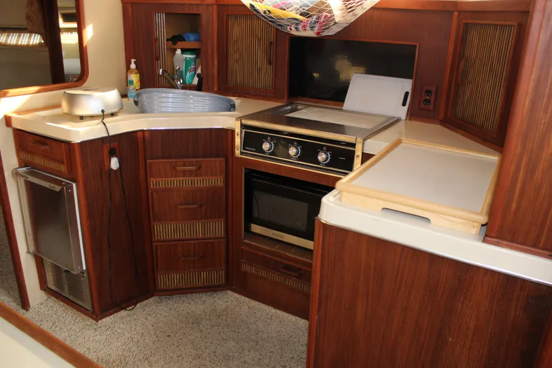 Slide: The Image of 1986 Searay 340 Express yacht kitchen with stove, sink, and wooden cabinetry. - 11