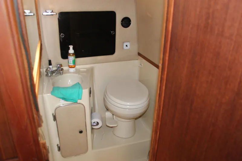 Slide: The Image of 1986 Searay 340 Express boat bathroom with sink, toilet, and wooden accents. - 12