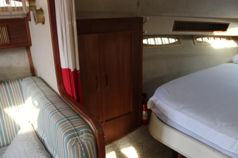 Slide: The Image of 1986 Searay 340 Express cabin interior with bed, striped sofa, and wooden cabinet. - 14