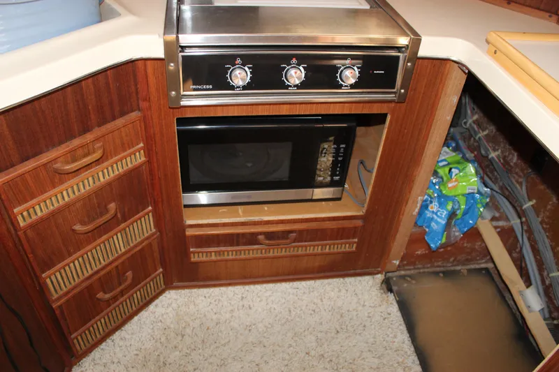 Slide: The Image of 1986 Searay 340 Express kitchen with stove, microwave, and wooden cabinetry. - 18