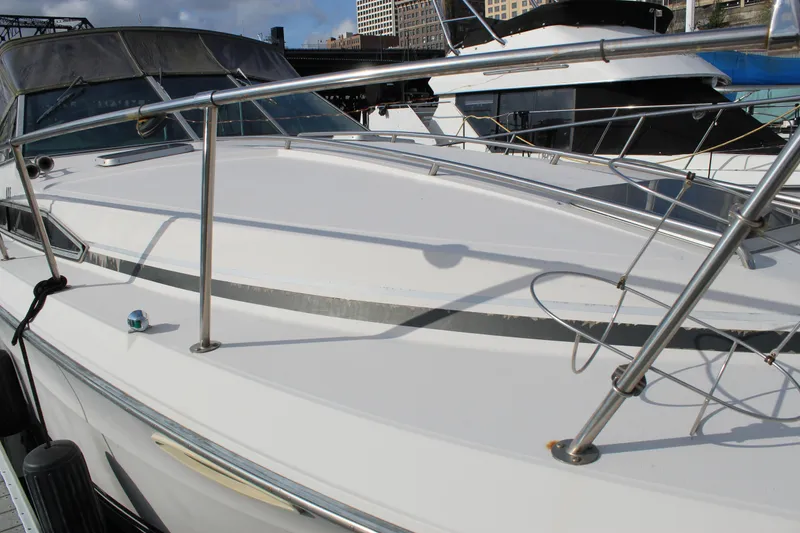 Slide: The Image of 1986 Searay 340 Express boat docked, showcasing sleek white deck and stainless steel railings. - 2