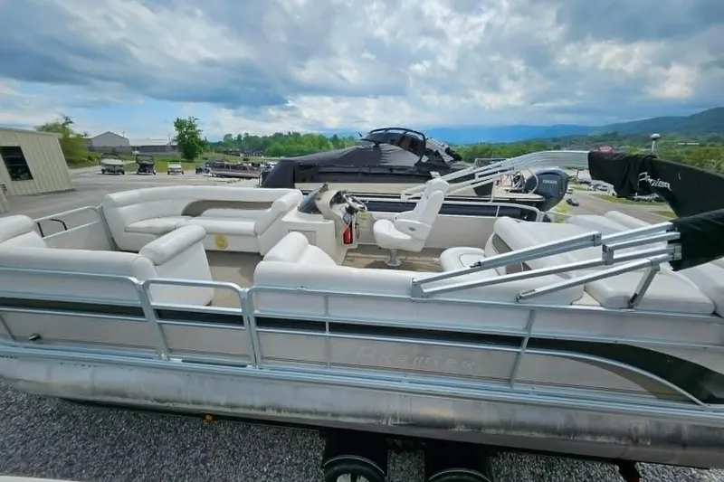 Slide: The Image of 2007 Premier 225 Legend RE pontoon boat with spacious seating, parked outdoors under cloudy skies. - 8