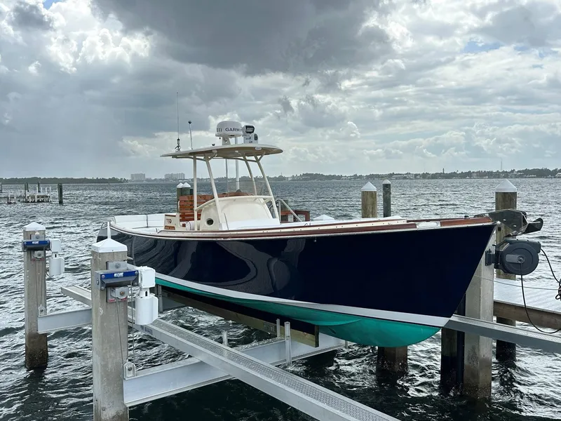 Slide: The Image of 2002 Hinckley Talaria 29 C boat docked on a lift under cloudy skies. - 2