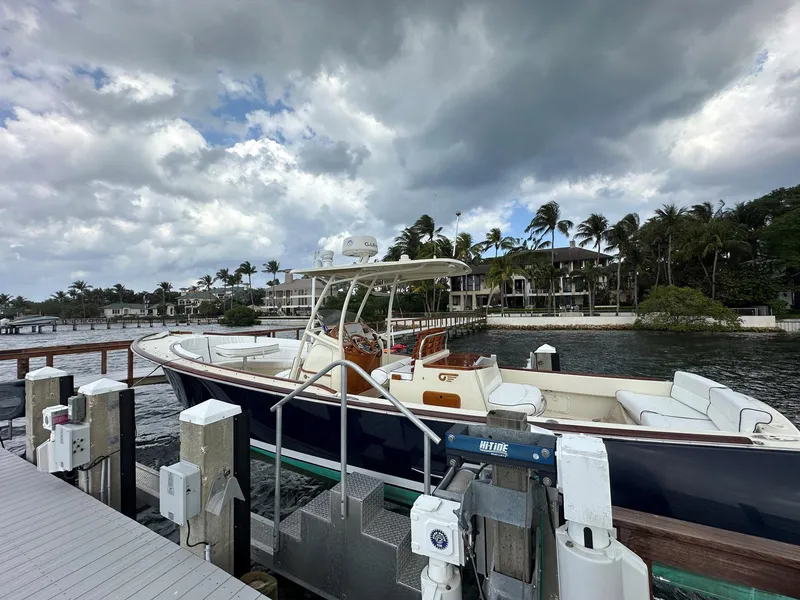 Slide: The Image of 2002 Hinckley Talaria 29 C docked by waterfront homes under cloudy skies. - 5