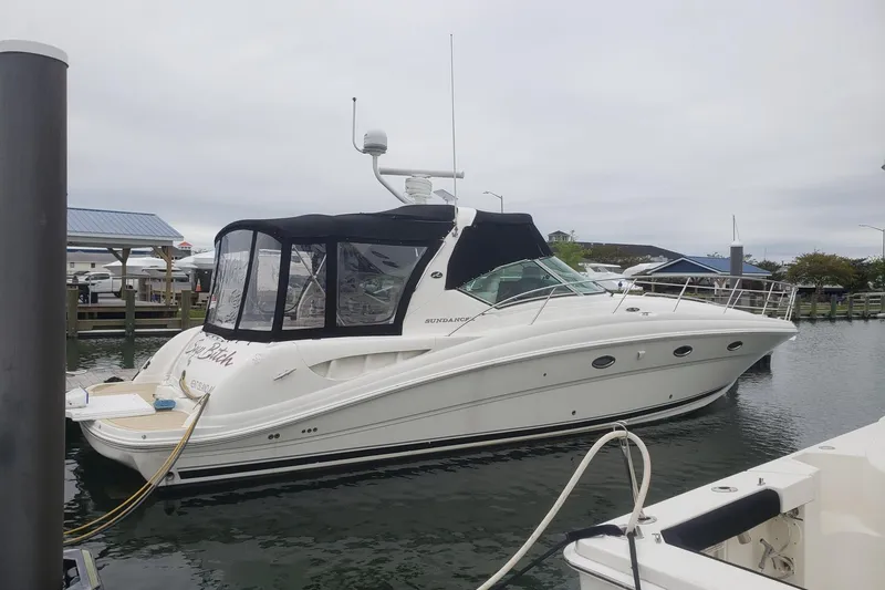 The Image of 2003 Sea Ray 420 Sundancer yacht docked at marina, featuring sleek design and black canopy. - 0