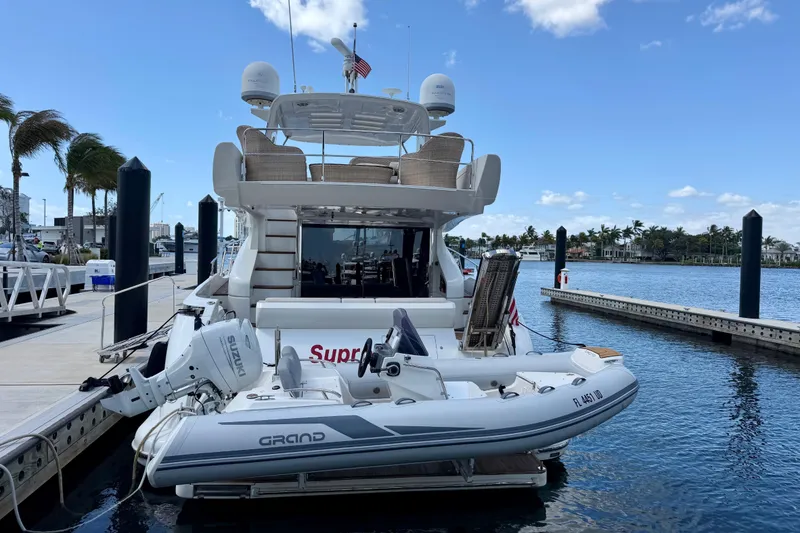 Slide: The Image of Azimut 60 yacht from 2013 docked with inflatable boat, clear sky, and palm trees. - 23