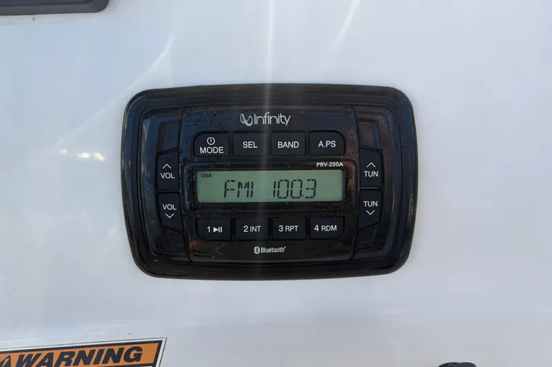 Slide: The Image of Infinity stereo system on a 2021 NauticStar 227 XTS, displaying FM 100.3. - 16