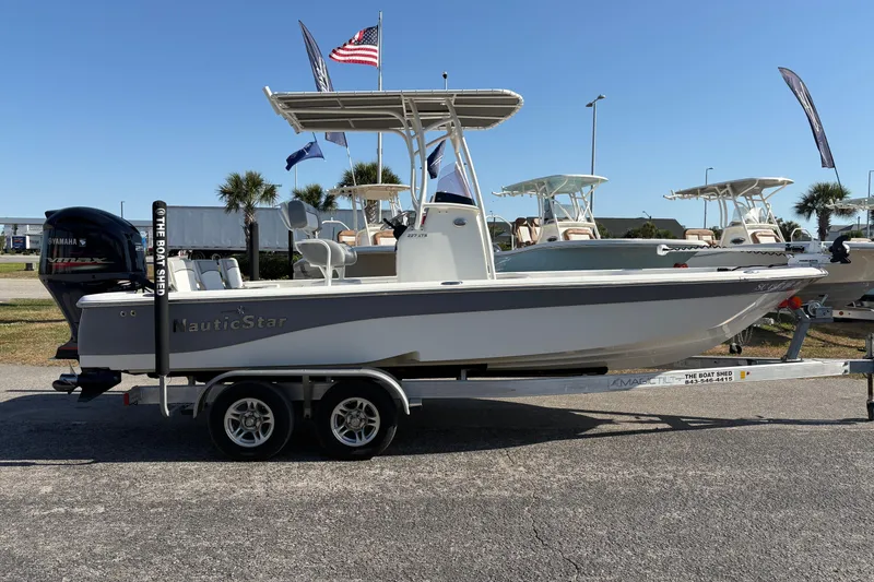 Slide: The Image of 2021 NauticStar 227 XTS boat on trailer, displayed outdoors with flags and palm trees. - 3