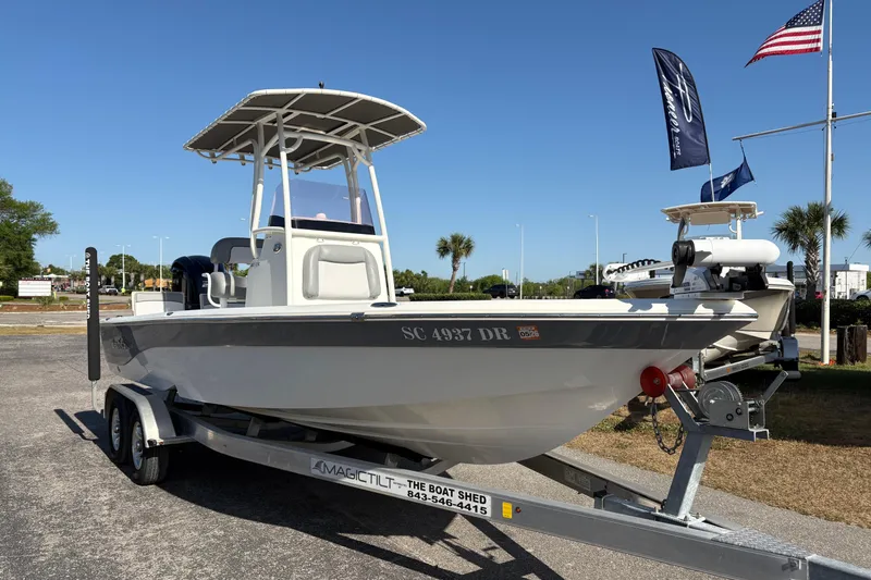 Slide: The Image of 2021 NauticStar 227 XTS boat on trailer, displayed outdoors with flags in the background. - 4