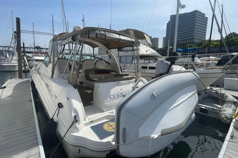 Slide: The Image of 2003 Sea Ray 340 Sundancer docked at marina, showcasing sleek design and spacious interior. - 2