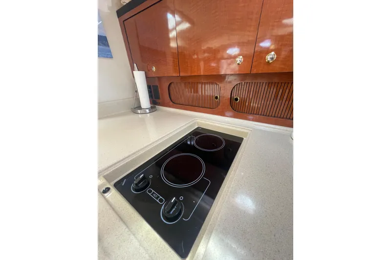 Slide: The Image of 2003 Sea Ray 340 Sundancer kitchen with electric stove and wooden cabinetry. - 33