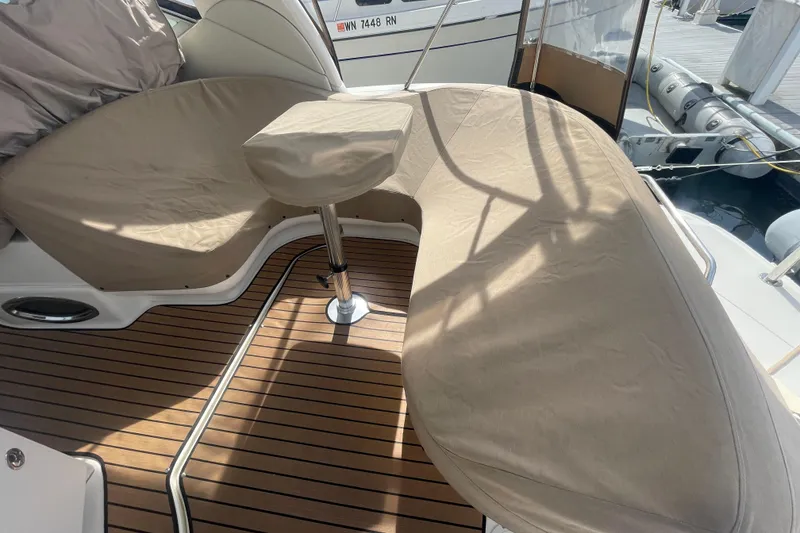 Slide: The Image of 2003 Sea Ray 340 Sundancer boat interior with cushioned seating and wooden deck. - 56