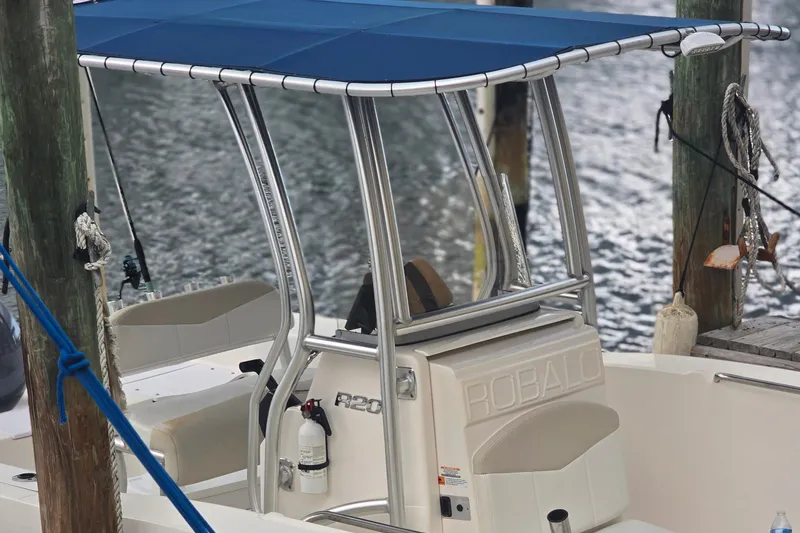 Slide: The Image of 2015 Robalo R200 Center Console boat docked with blue canopy and safety equipment. - 7