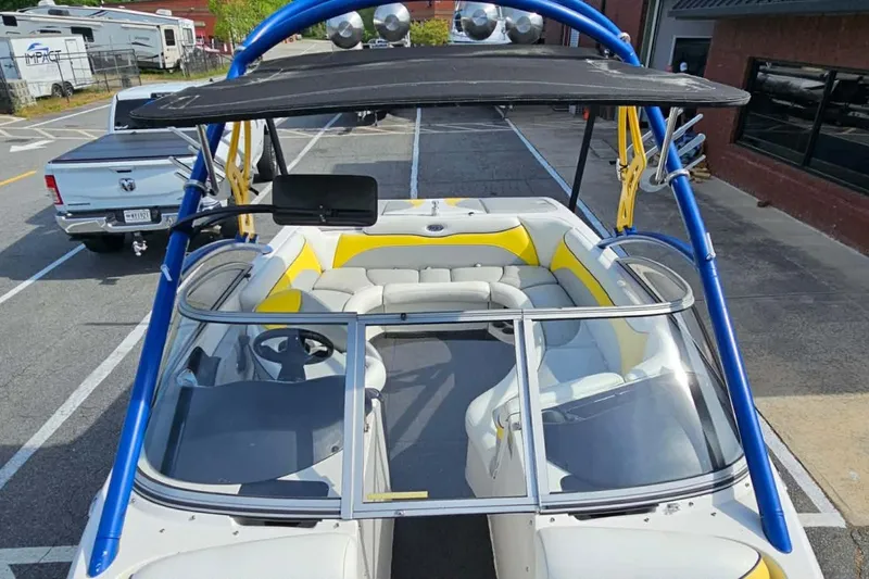 The Image of 2006 Tigé 22Ve boat with blue tower and yellow-accented seating in a parking lot. - 11