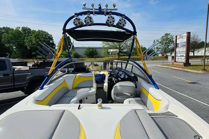 Slide: The Image of 2006 Tigé 22Ve boat with yellow accents, parked outdoors, featuring a wakeboard tower and speakers. - 13