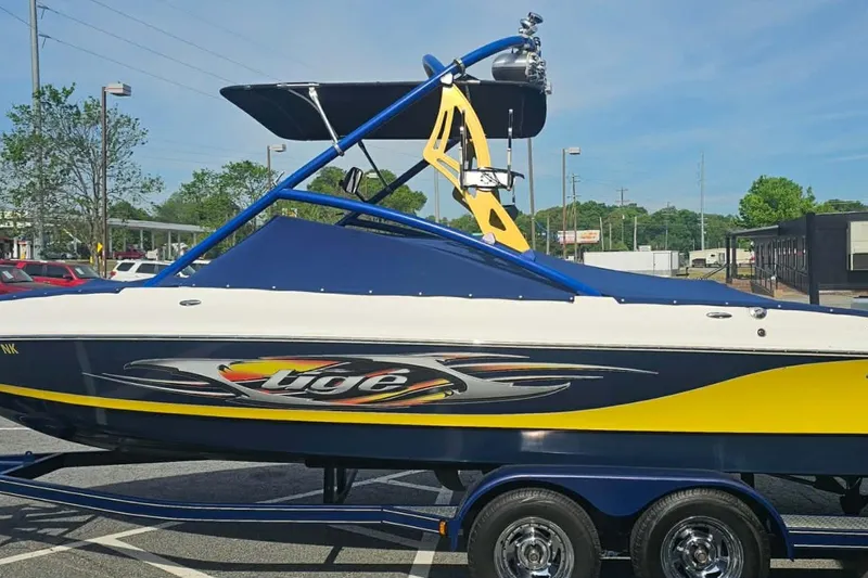 The Image of 2006 Tigé 22Ve boat with vibrant yellow and blue design on a trailer. - 3