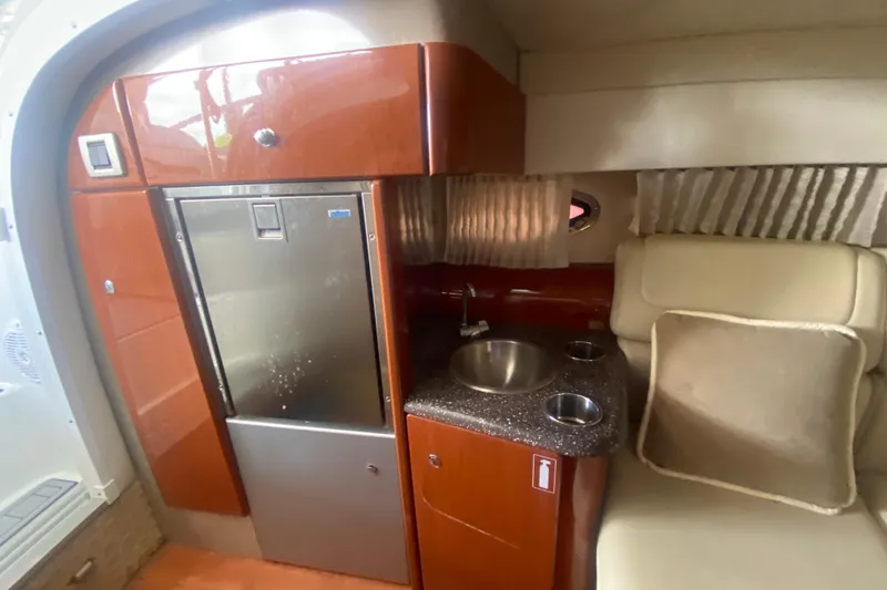 Slide: The Image of 2007 Formula 310 Sun Sport cabin with kitchenette, featuring sink, fridge, and seating area. - 21