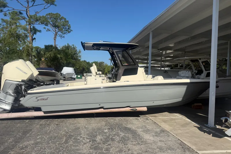 The Image of 2026 Scout 281 XSS boat with Mercury engine, parked under a canopy. - 1