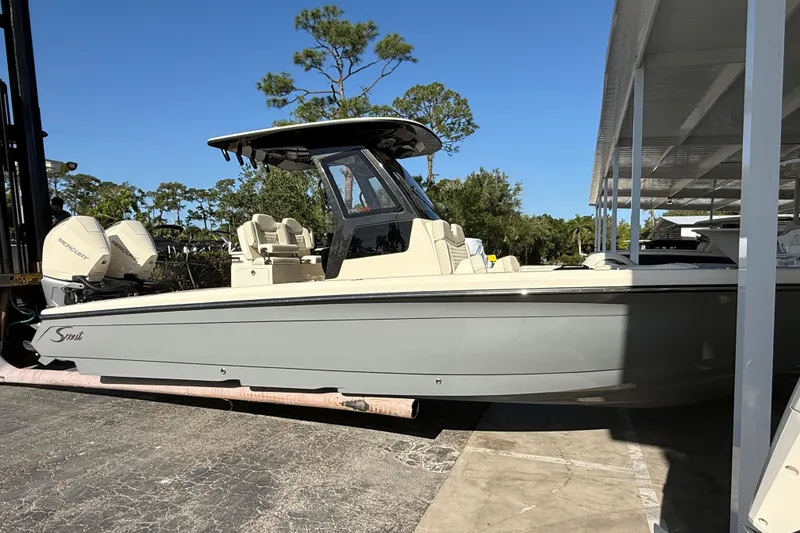 Slide: The Image of 2026 Scout 281 XSS boat with dual Mercury engines, parked outdoors under clear blue sky. - 4