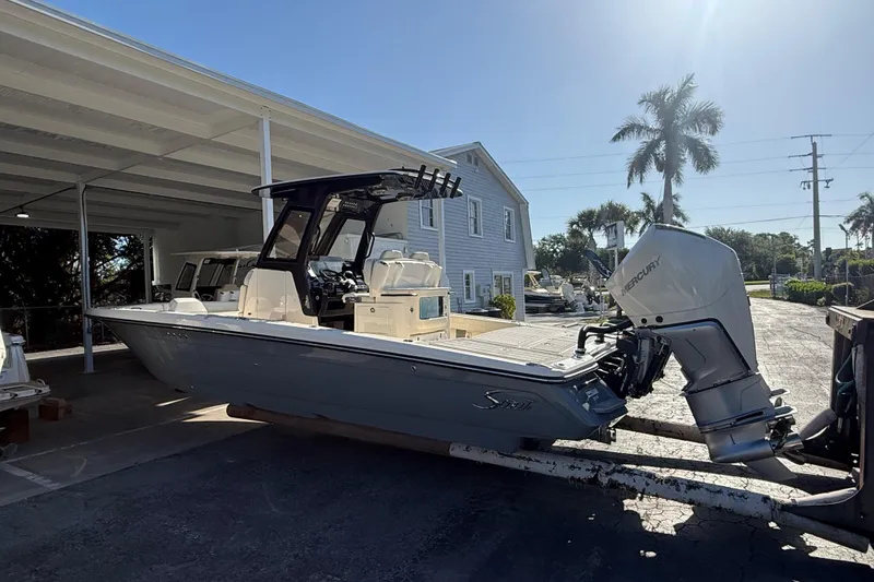 Slide: The Image of 2026 Scout 281 XSS boat with Mercury engine, parked under a canopy near palm trees. - 6