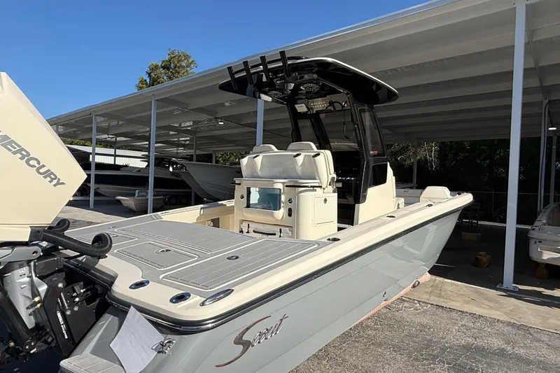Slide: The Image of 2026 Scout 281 XSS boat with Mercury engine, parked under a covered area. - 7