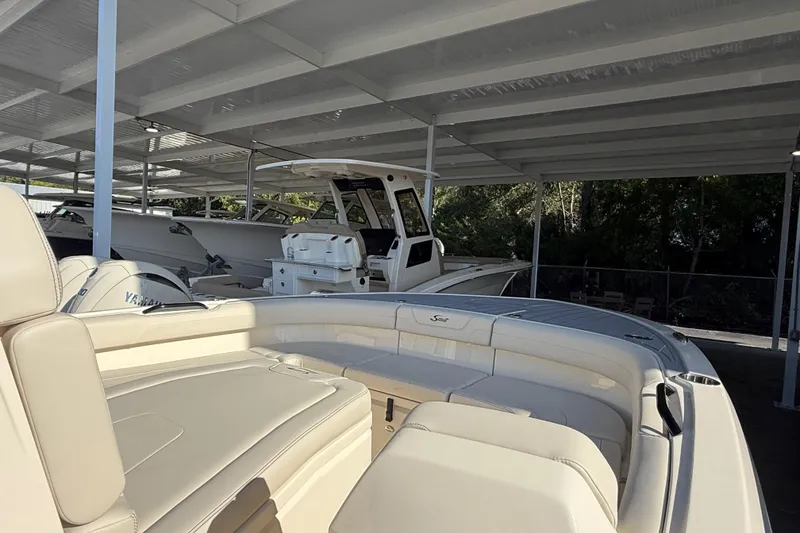 Slide: The Image of 2026 Scout 281 XSS boat with beige seating, parked under a covered area. - 9