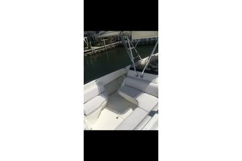 Slide: The Image of 2001 Intrepid 322 Cuddy boat interior with white seating near a dock. - 10