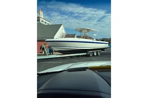 Slide: The Image of 2001 Intrepid 322 Cuddy boat on trailer near building under blue sky. - 7