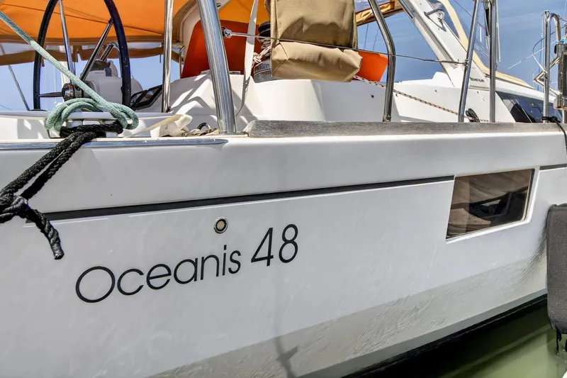 Slide: The Image of 2012 Beneteau Oceanis 48 sailboat with orange canopy, docked in calm waters. - 10