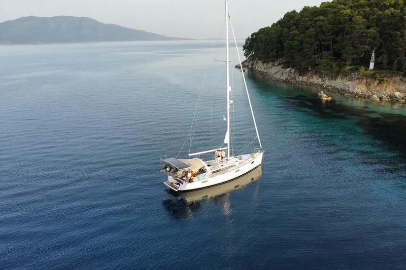 Slide: The Image of Sailboat Beneteau Oceanis 48 (2012) anchored near a forested coastline. - 3