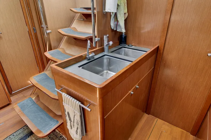 Slide: The Image of Interior of 2012 Beneteau Oceanis 48 yacht featuring a compact wooden kitchen area. - 38