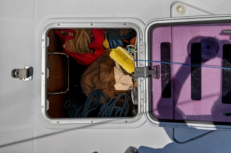 Slide: The Image of Open storage compartment on 2012 Beneteau Oceanis 48 yacht, containing ropes and cleaning supplies. - 61