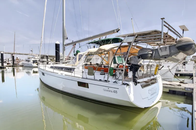 Slide: The Image of 2012 Beneteau Oceanis 48 sailboat docked in a marina, reflecting on calm water. - 8