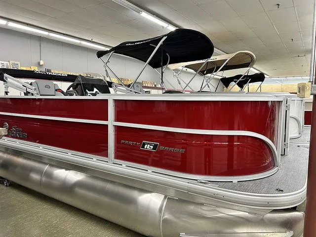 The Image of Red Sun Tracker Party Barge 16 DLX pontoon boat, 2026 model, in a showroom. - 1