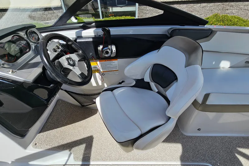 Slide: The Image of Interior of a 2014 Scarab 215 boat featuring a sleek steering wheel and comfortable seating. - 13