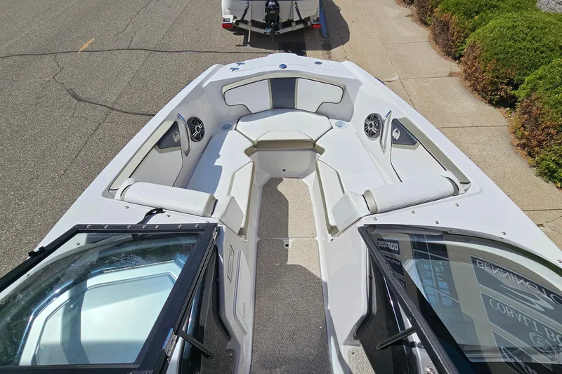 Slide: The Image of 2014 Scarab 215 boat interior with white seating and speakers, parked on a street. - 16